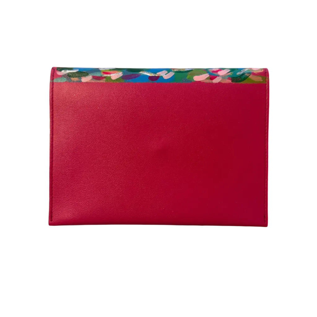 A bright pink faux-leather card holder or sleeve with a colorful floral patterned top border, placed on a white marble surface.