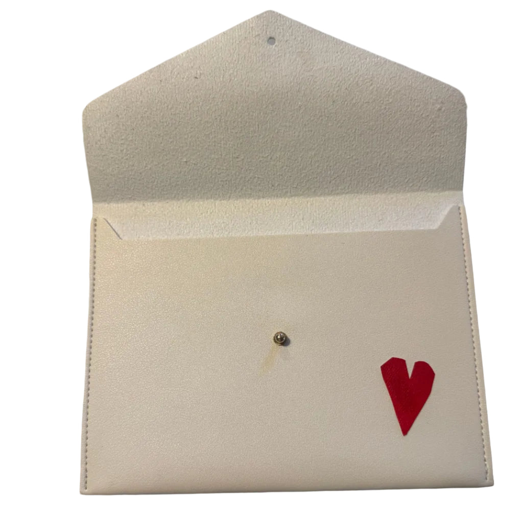 An off-white textured envelope-style card holder or wallet with a small red heart on the front flap, photographed on a gray marble surface.