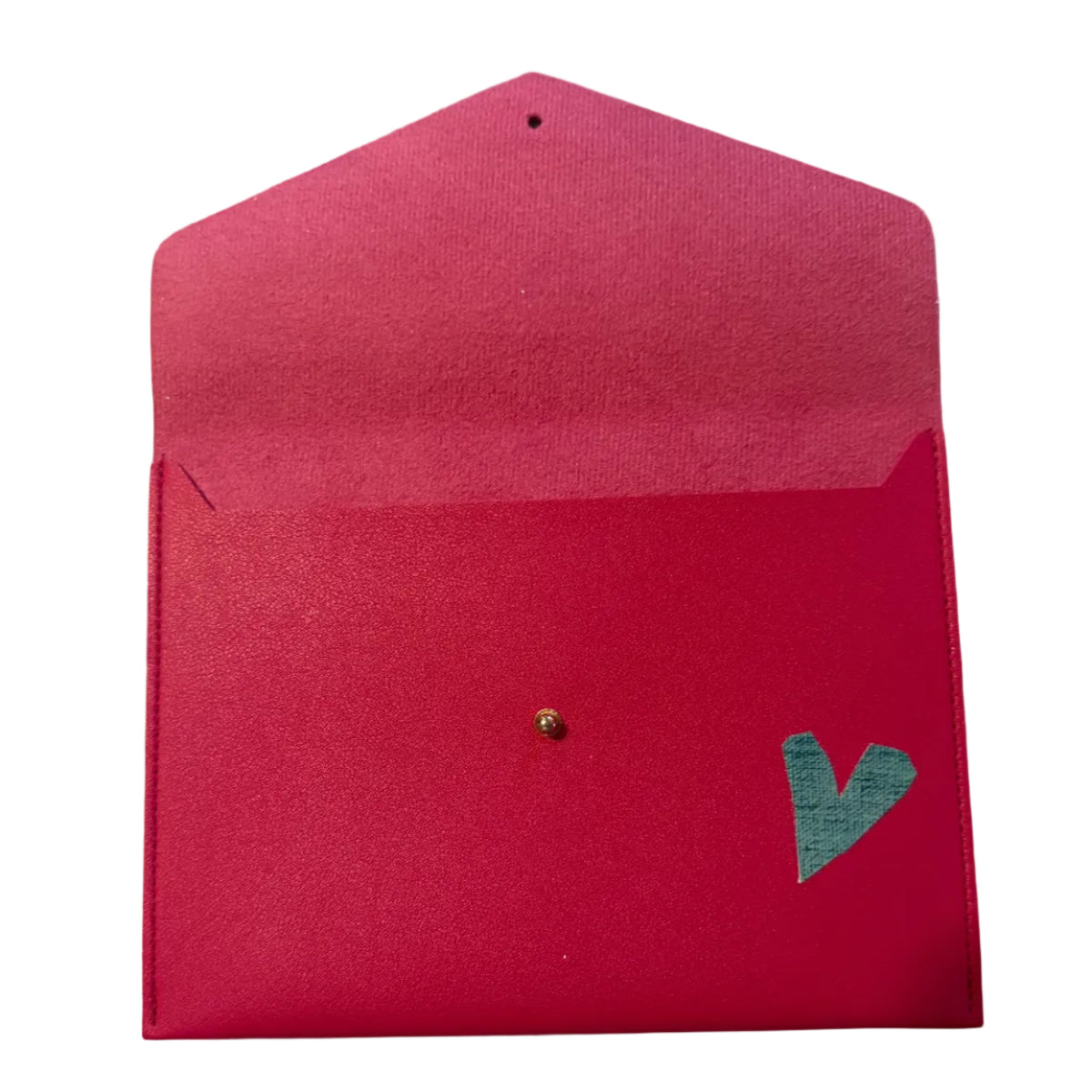 A bright pink textured paper envelope with a small gold stud and a green heart-shaped embellishment, shown on a white marble surface.