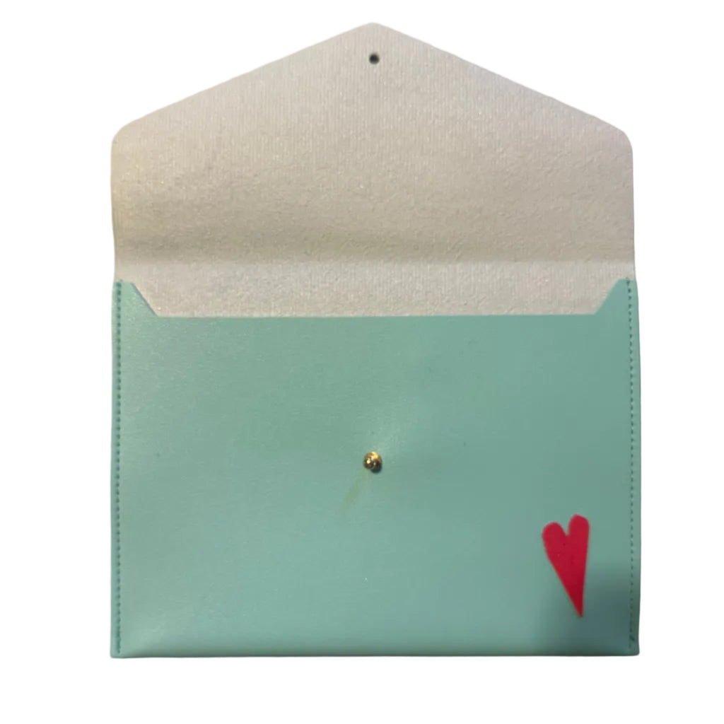 A mint green faux leather card holder or small pouch with a white textured interior lining, a small gold stud in the center, and a red heart printed in the bottom right corner, displayed on a light marble surface.