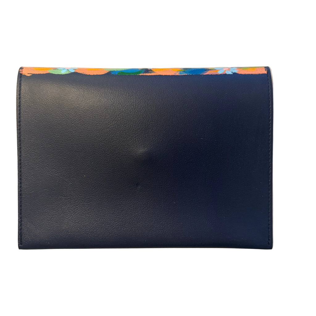 A dark navy blue leather wallet or card holder with a colorful abstract patterned trim along the top edge, placed on a white marble surface.